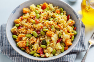 Cooked golden real quinoa seeds with vegetables, served on a plate.